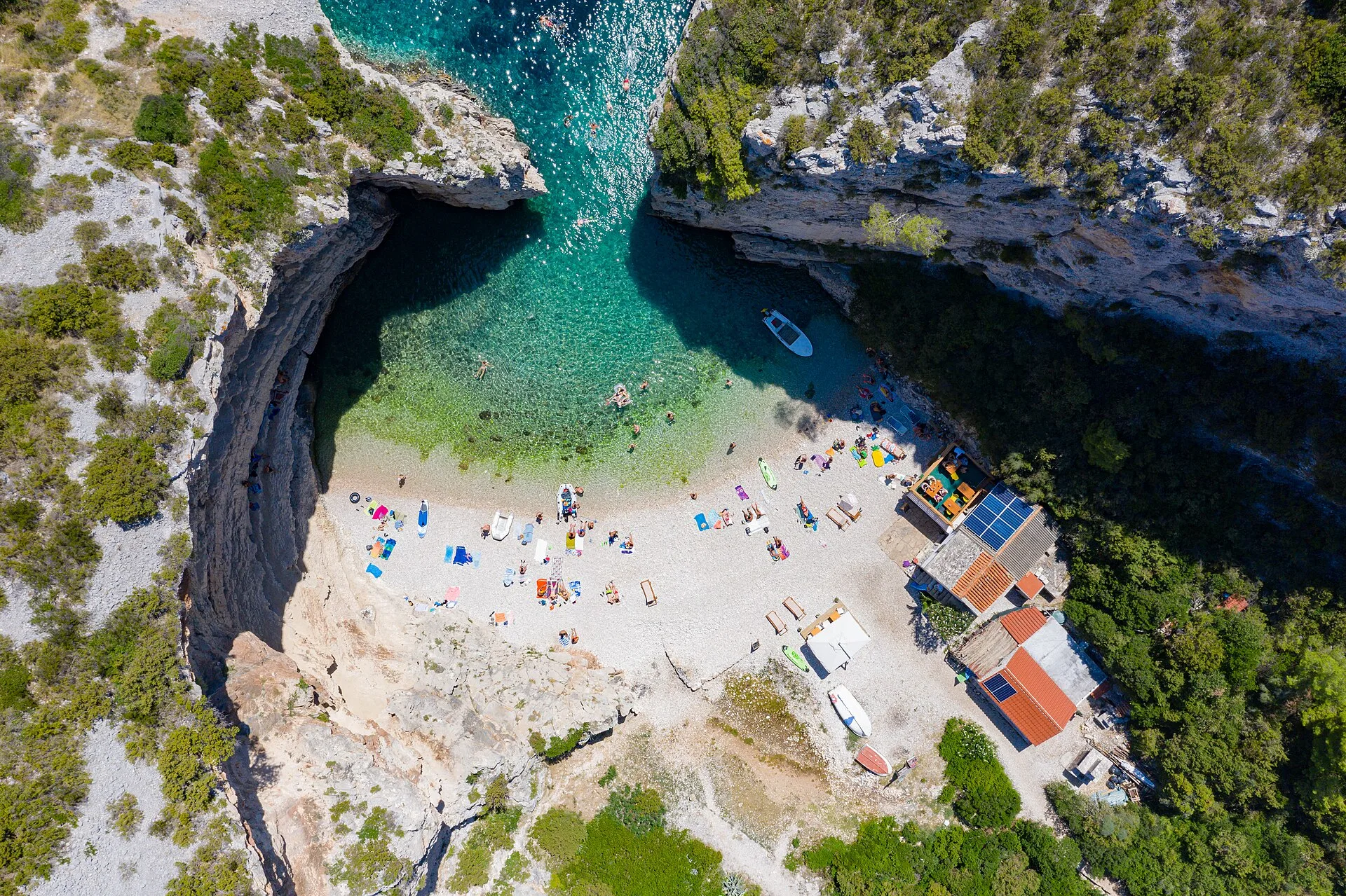 Aerial drone view of Stiniva Cove on Vis island, Croatia, showing the narrow rock-walled entrance and turquoise water