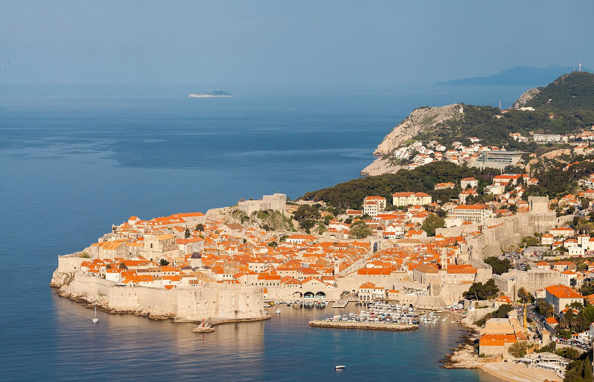 Elevated view of Dubrovnik's walled Old Town peninsula in warm evening light, with the Adriatic and islands beyond