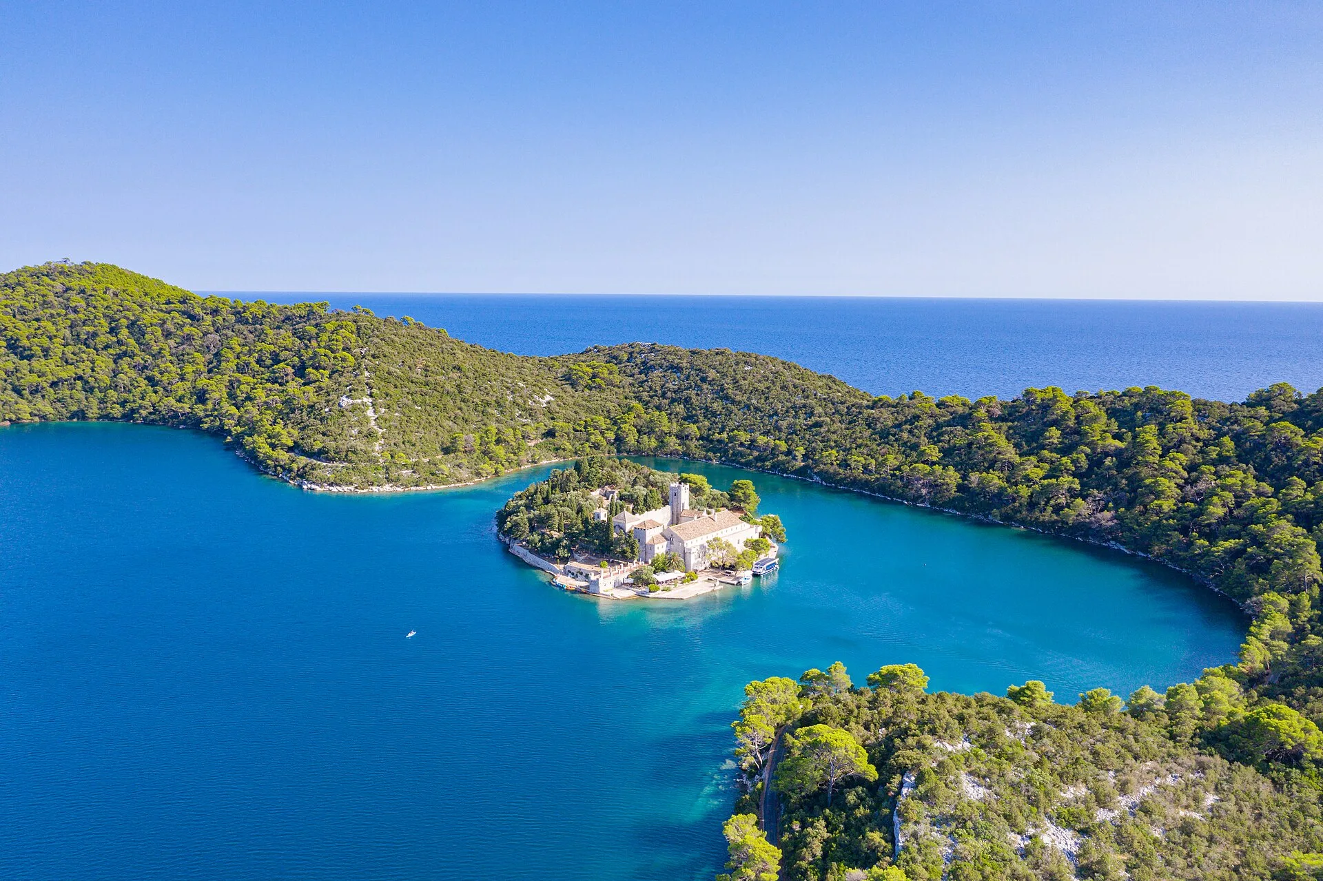 Aerial view of the small monastery island of St. Mary in the middle of a saltwater lake in Mljet National Park, Croatia, surrounded by pine forest