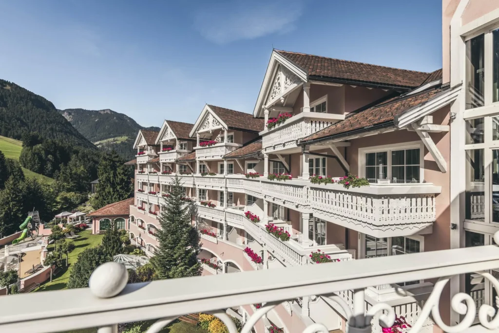 Elevated view of Cavallino Bianco Family Spa Grand Hotel with the Dolomites behind, Ortisei