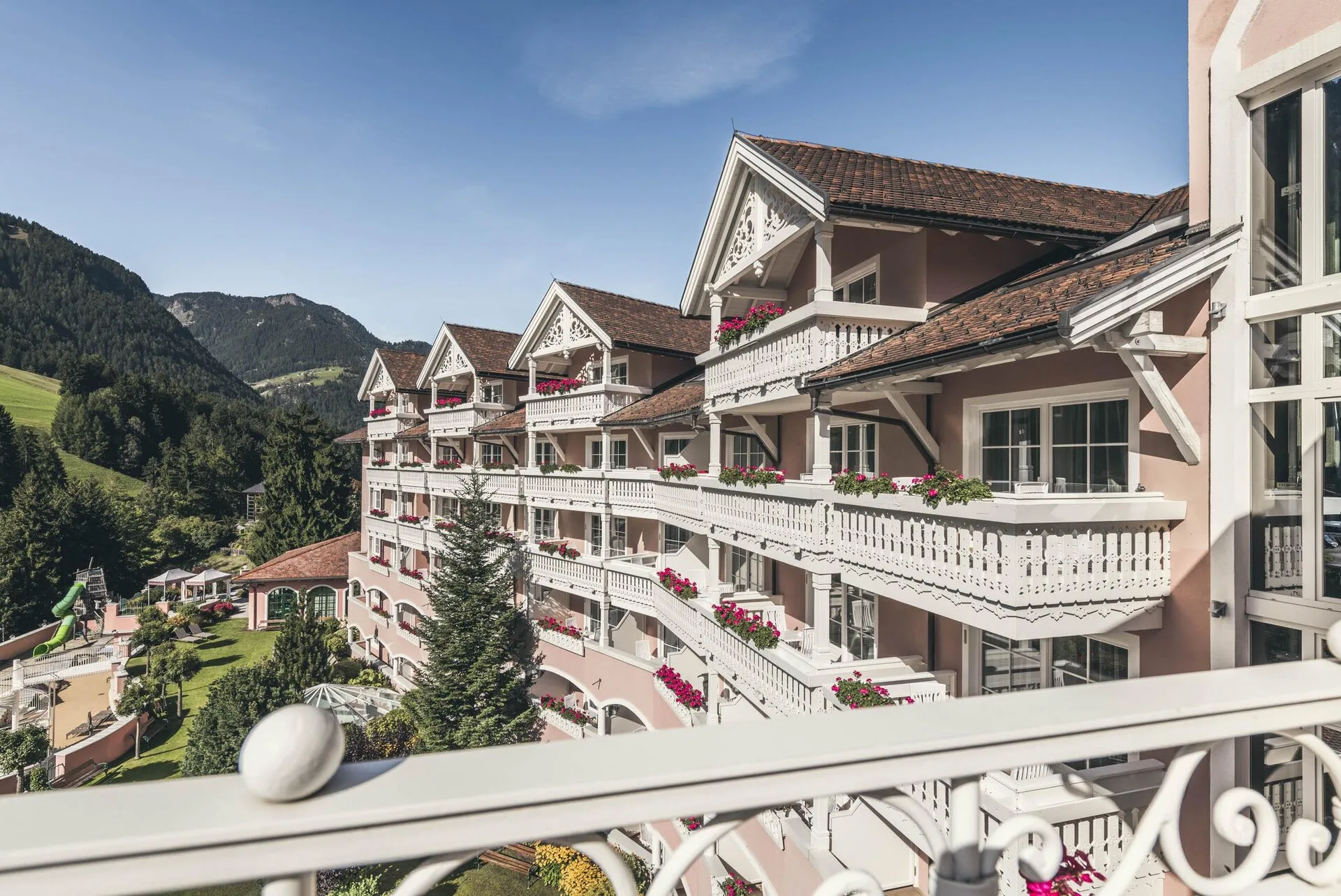 Elevated view of Cavallino Bianco Family Spa Grand Hotel with the Dolomites behind, Ortisei