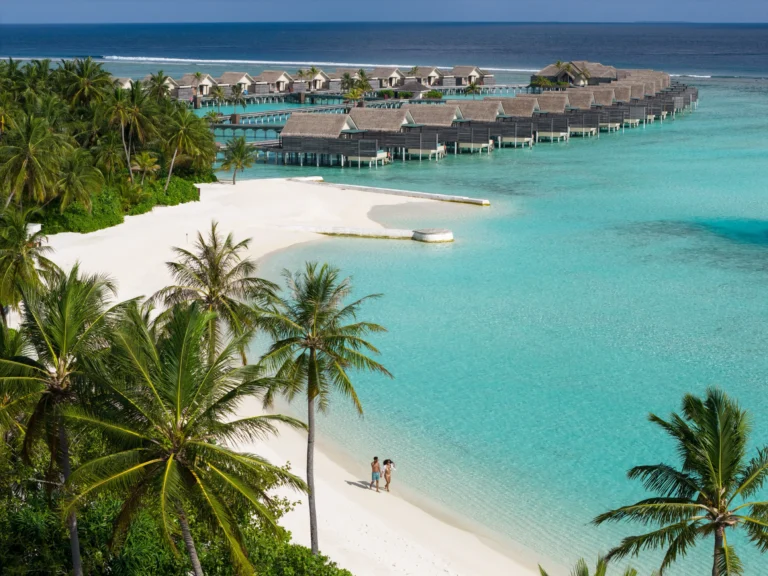 Aerial view of Niyama's beach, lagoon and dining pavilion with a couple walking along the shoreline