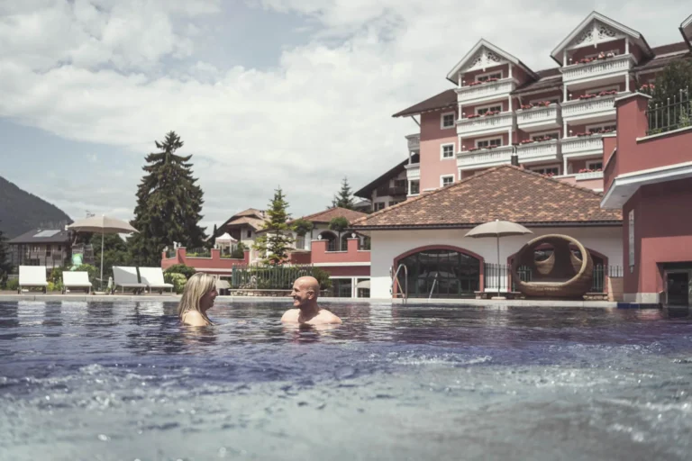 Outdoor heated pool at Cavallino Bianco with the hotel building behind