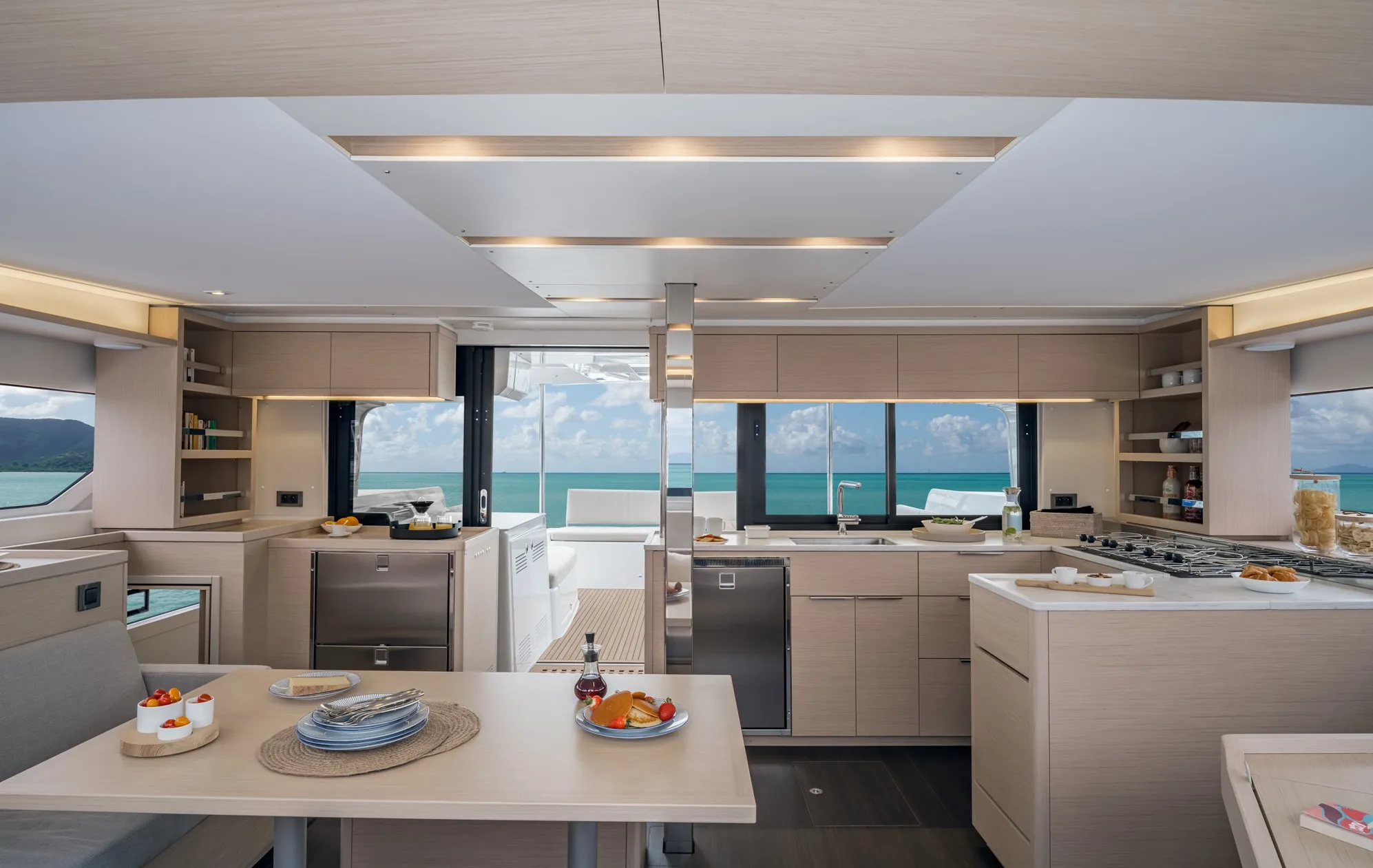 Interior saloon and galley of a Lagoon 46 catamaran with a dining table and panoramic windows onto the cockpit