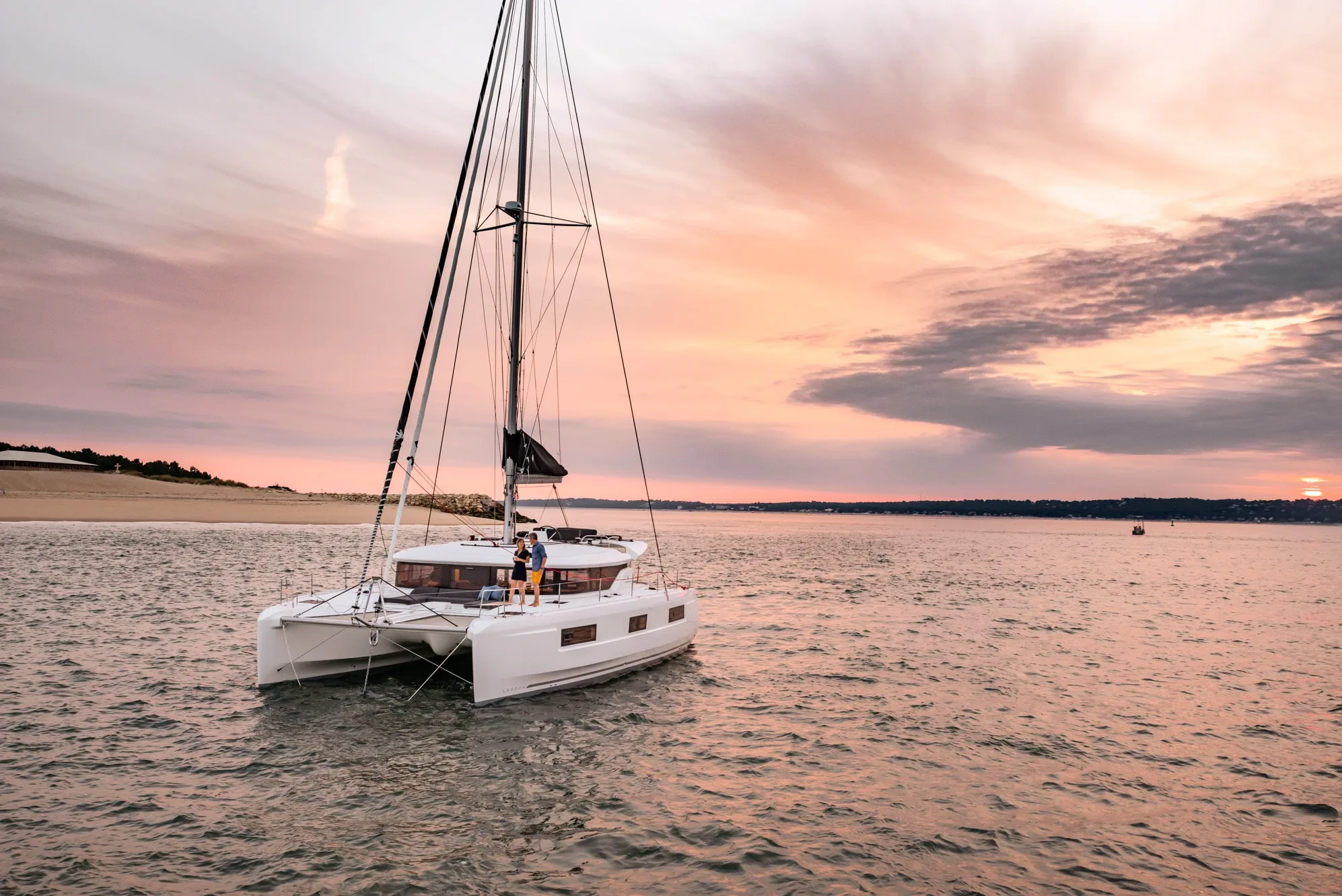 A Lagoon 46 catamaran lying at anchor in a calm bay at sunset, its twin hulls and wide bridge deck visible
