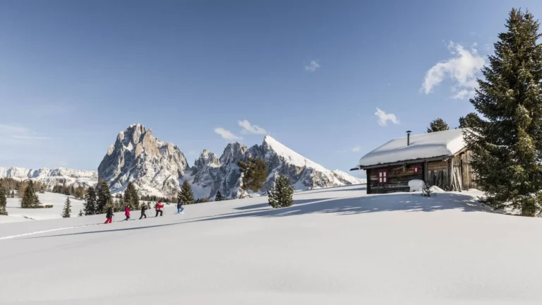 Winter hiking trail near Ortisei with a mountain hut and the Dolomites behind