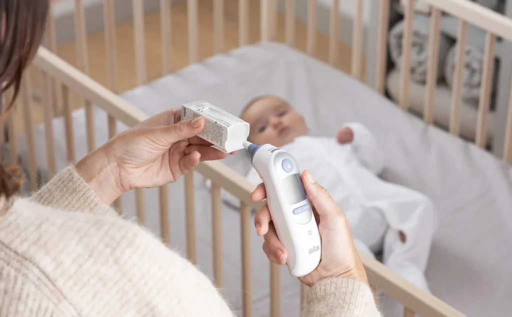 Parent taking child's temperature with Braun ThermoScan 7 IRT6520 ear thermometer