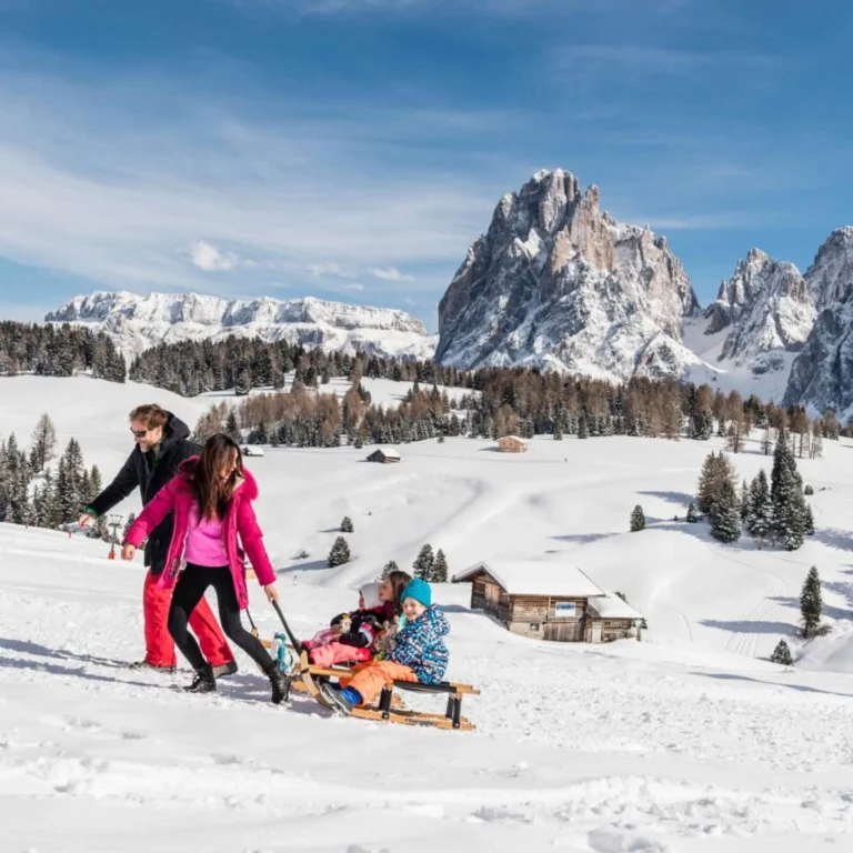 Family pulling a sledge through snow in the Dolomites near Ortisei