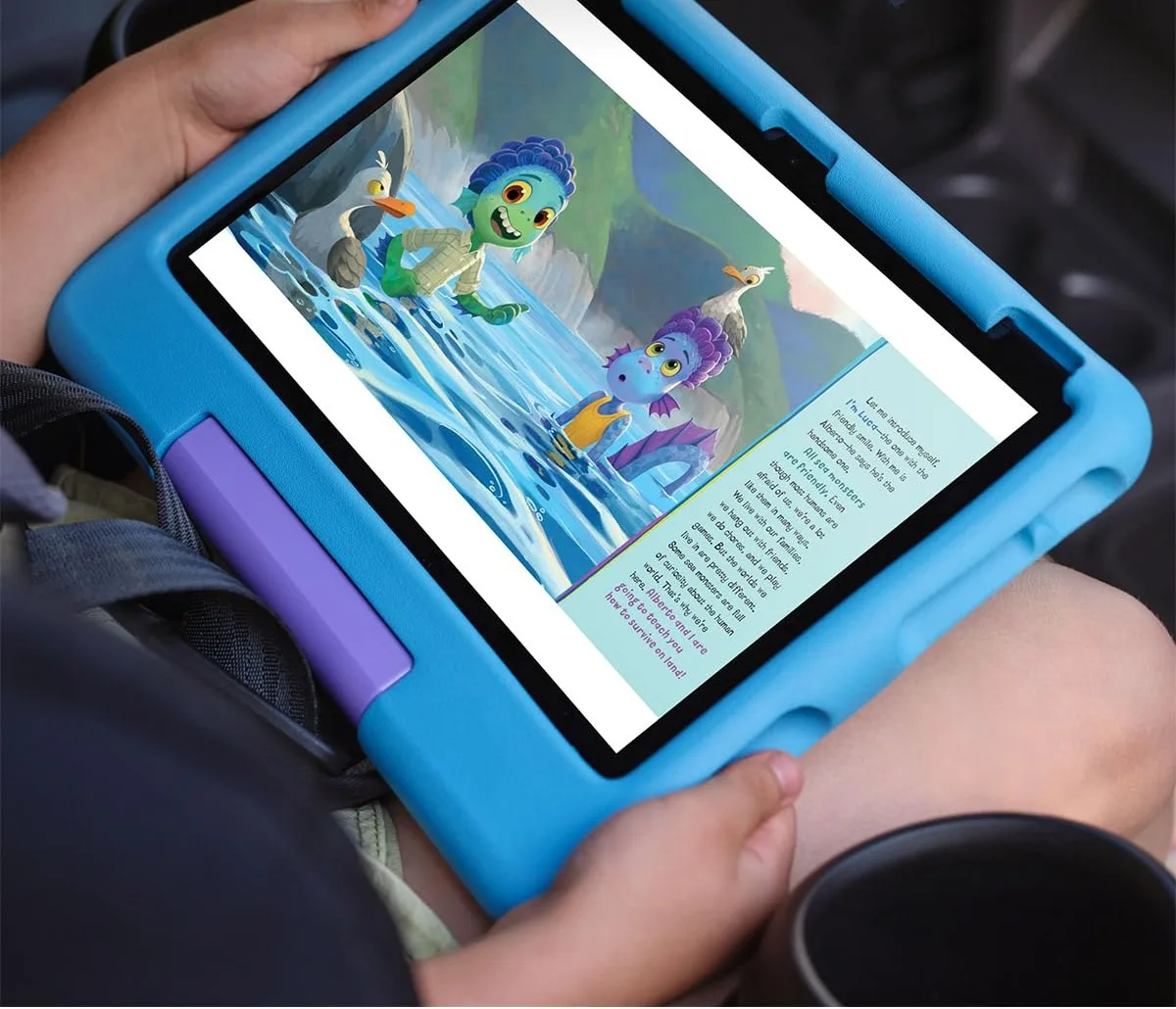 Amazon Fire HD 10 Kids tablet with foam case and kickstand beside a children’s travel bag on a hotel bed