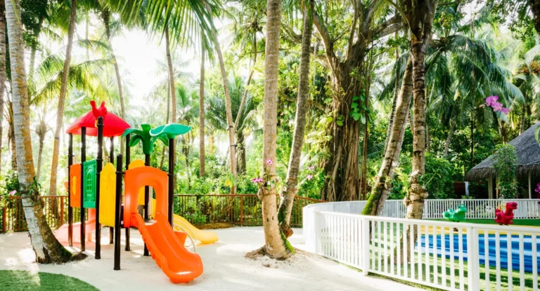 An adult and a young child ride bicycles along a sandy path through dense tropical vegetation at Niyama Private Islands Maldives