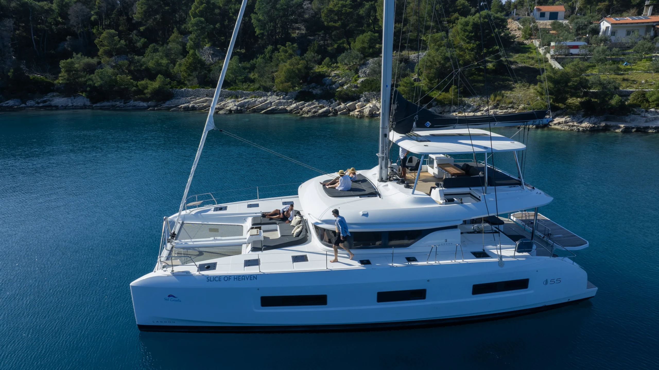 The Lagoon 55 catamaran Slice of Heaven at anchor in a Croatian bay, seen from the water with its flybridge and foredeck lounge