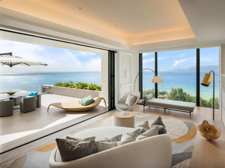 Suite living area with a rounded sofa opening to a terrace and the sea