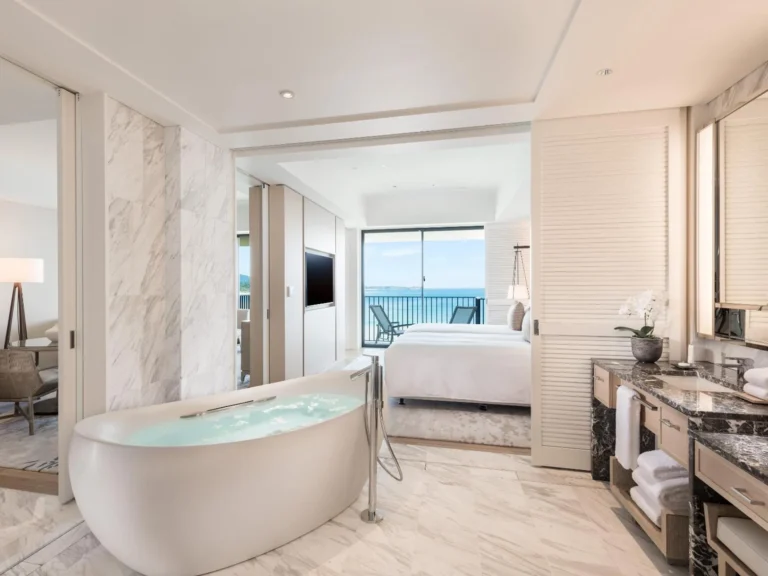 Freestanding tub with the bedroom and balcony visible beyond