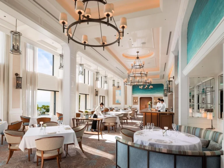 SHIROUX dining room with chandeliers, white tablecloths and a teal mural