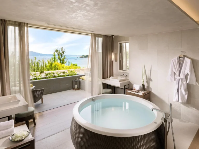 Round bath in a spa room beside a window with a view of the sea