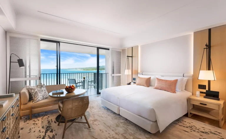 Twin room with a round table and a sea-view balcony in daylight