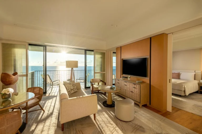 Suite living room with a sofa and cane chairs in low sun looking over the sea