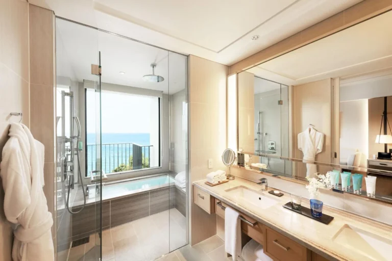 Bathroom with a glass-walled shower and tub looking out to the sea