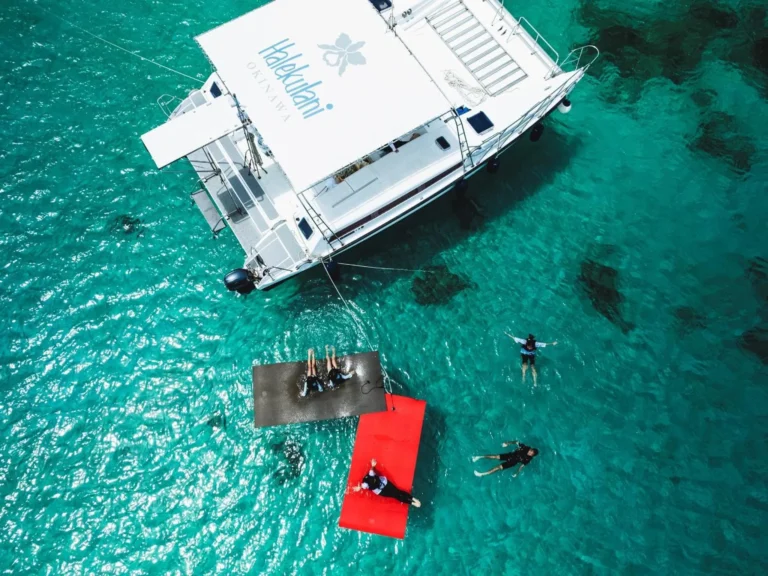 Aerial of a Halekulani catamaran with swimmers on floating mats and snorkellers in clear water