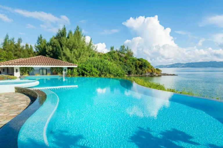 Infinity pool beside a tile-roofed pavilion with headland and sea beyond