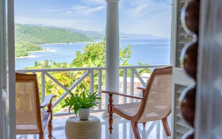 Cane-seat chairs on a white-railed balcony looking over the coast