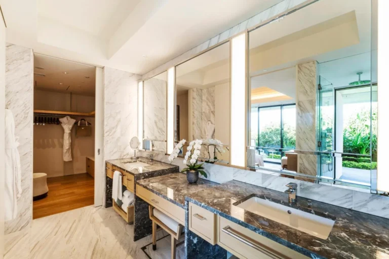 Villa bathroom with a long double vanity and a walk-in wardrobe behind a glass door