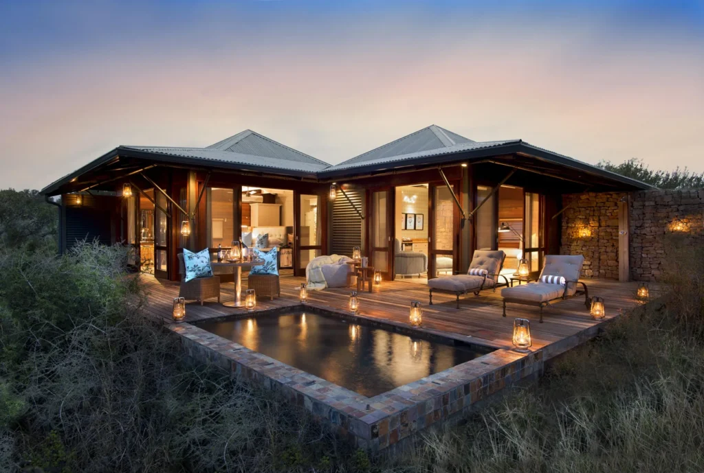 A Kwandwe Ecca Lodge suite with its deck and private plunge pool lit at dusk