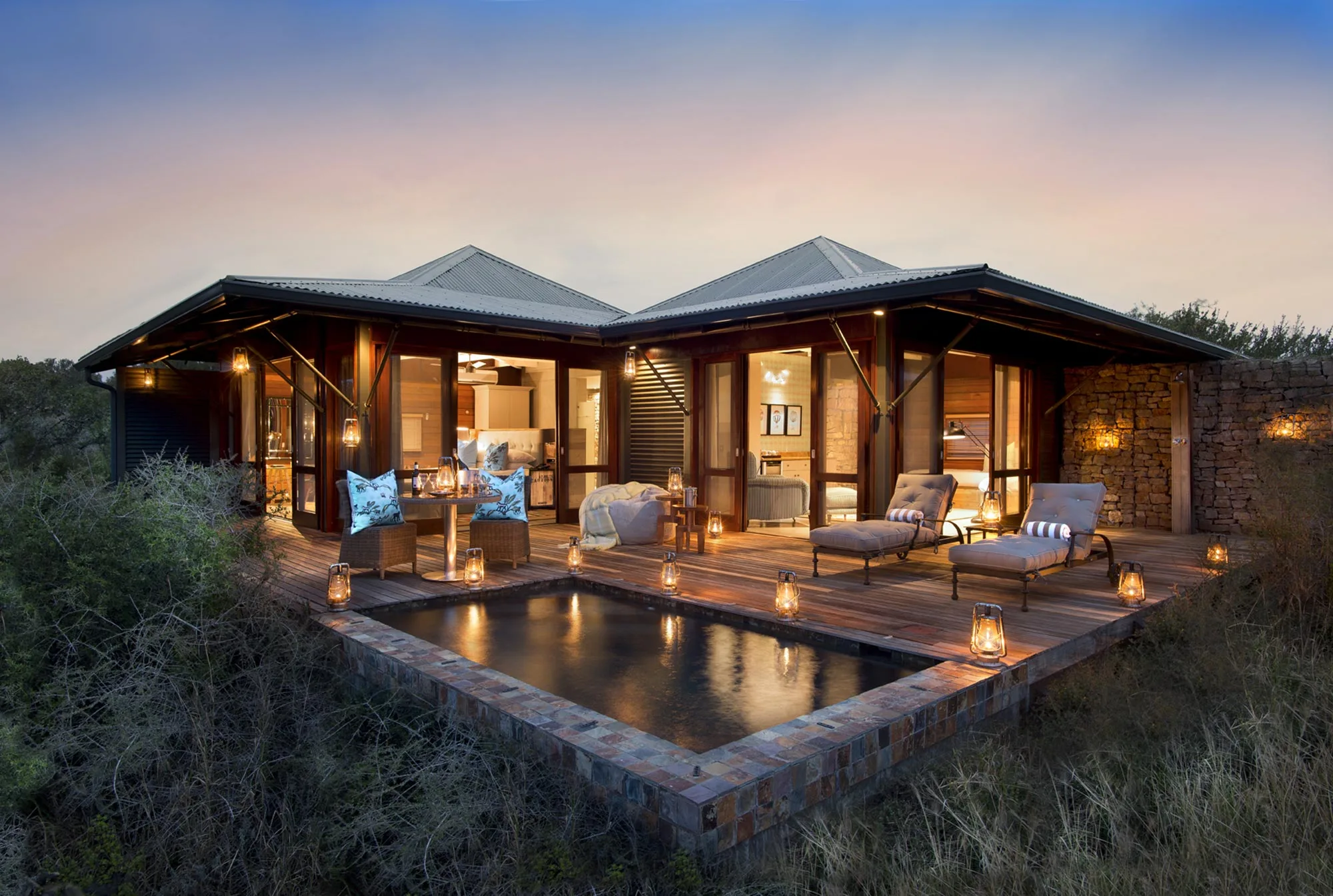 A Kwandwe Ecca Lodge suite with its deck and private plunge pool lit at dusk