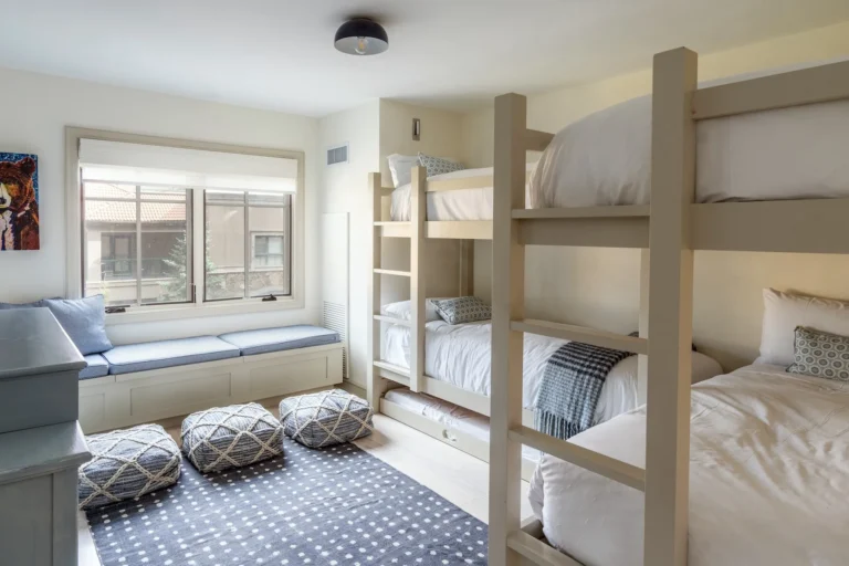 Children’s bedroom with built-in bunk beds, a window seat and two floor poufs