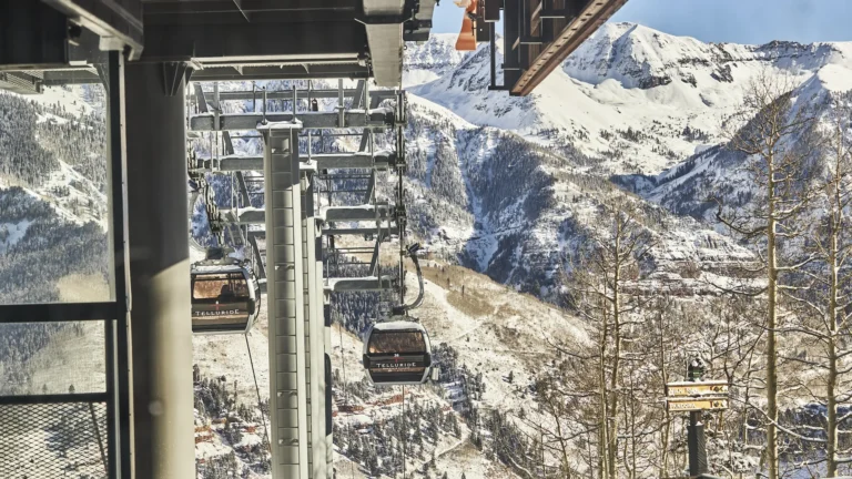 View from a gondola cabin over lift towers, cabins and snowy peaks above Telluride