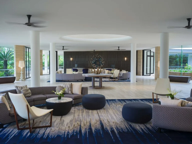 Open lobby lounge with curved sofas, round tables and pale columns