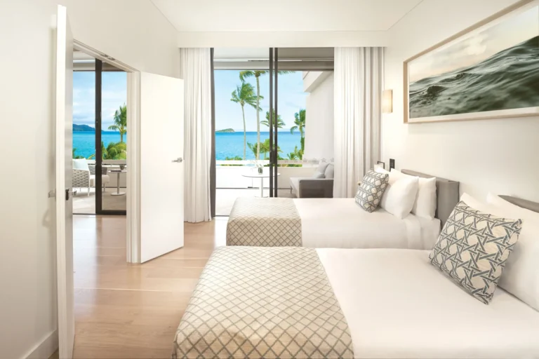 Twin-bed guest room with sliding doors to a balcony and sea view