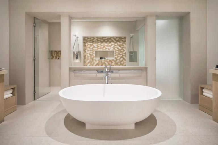 Open bathroom with a freestanding oval bath and mosaic feature wall