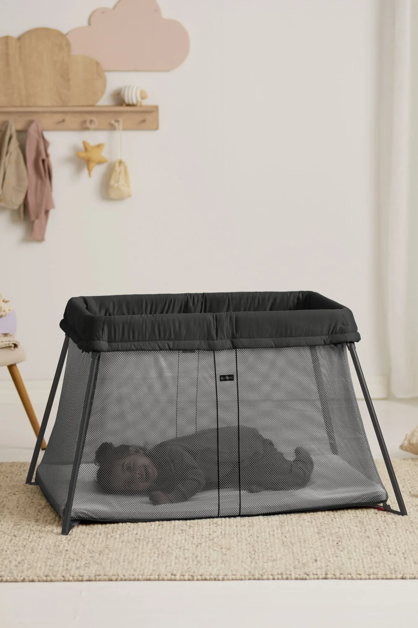 Folded BabyBjörn Travel Cot Light and mattress laid beside the open carry bag