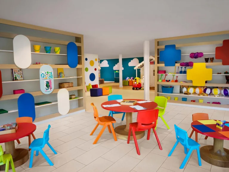 Colourful children's playroom with small round tables, bright chairs and shelving