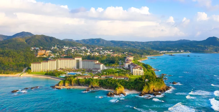 Aerial view of the resort with the Motobu hills and a rocky cove behind the hotel