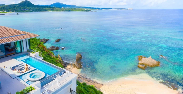 Aerial of a cliff villa with a private pool and hot tub above a turquoise cove