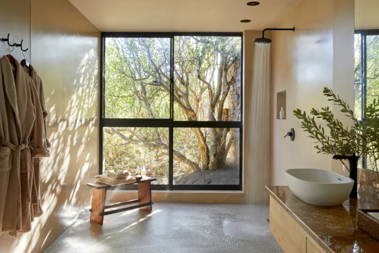 A suite bathroom at Kwandwe Ecca Lodge with a freestanding basin and a large window onto the thicket