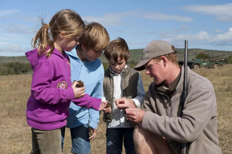 A ranger shows three children something he has found in the grass at Kwandwe Private Game Reserve
