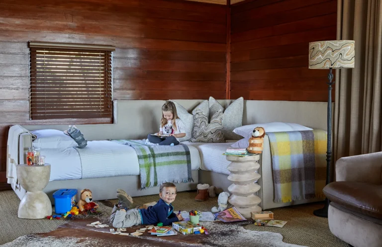 A suite at Kwandwe Ecca Lodge set up with twin beds, with two children at play