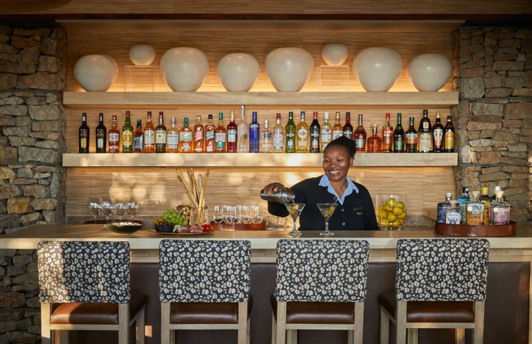 A staff member preparing a drink at the bar of Kwandwe Ecca Lodge