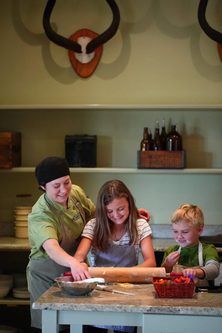A girl and a boy rolling out dough with a member of staff at Kwandwe Ecca Lodge