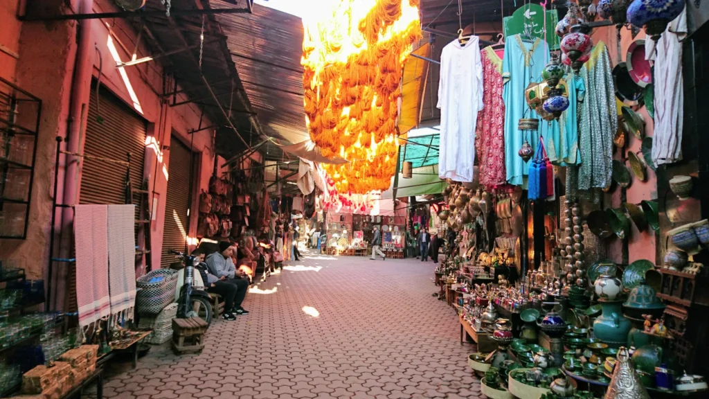 Busy pedestrian street in Marrakech with warm-toned historic architecture.