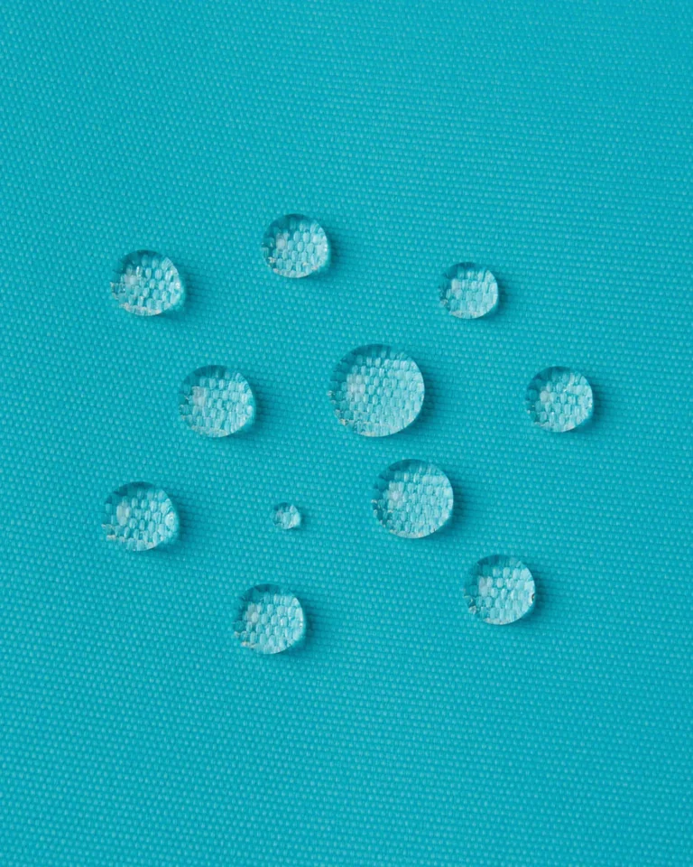 Round water droplets sitting on the surface of turquoise Reima outer fabric, shown as a macro close-up
