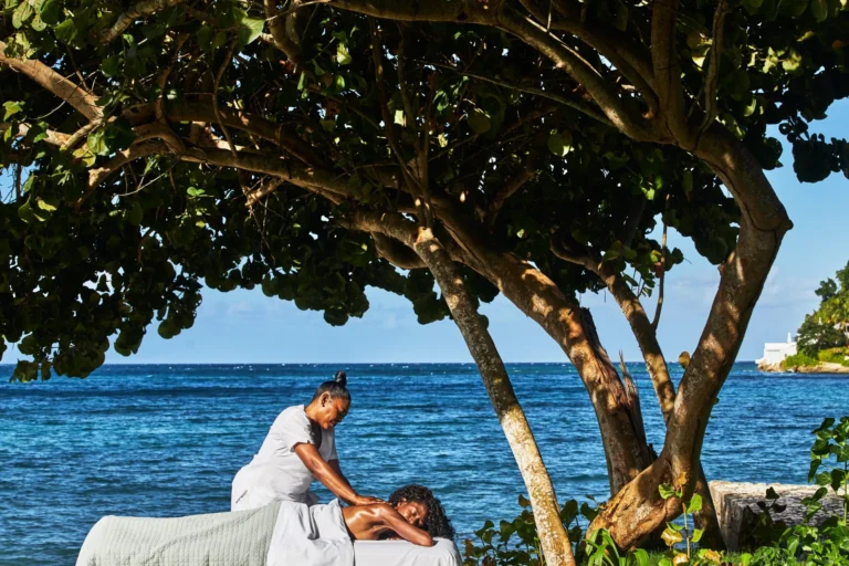 Massage on the shore beneath a spreading tree with the sea behind