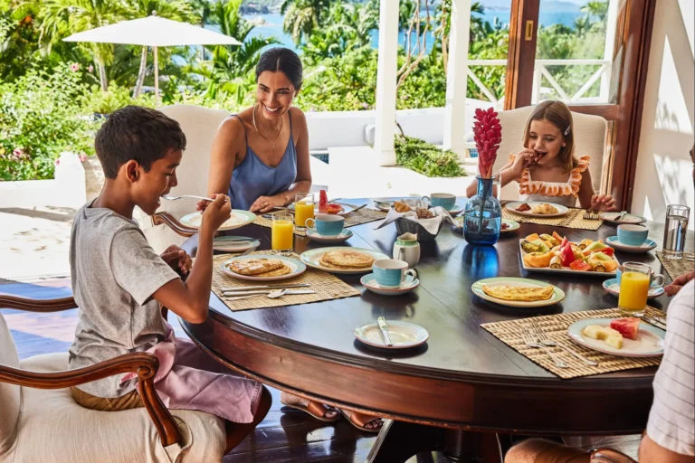 Mother and two children eating pancakes and fruit at a round breakfast table