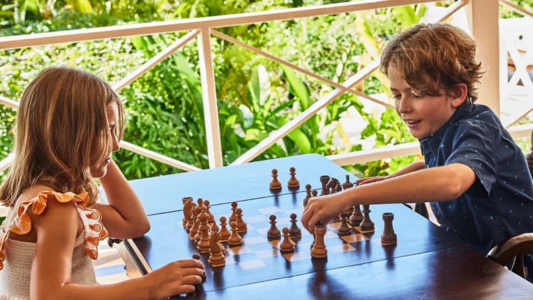Girl and boy playing chess at a veranda table