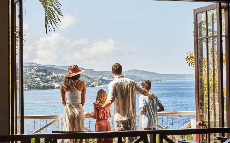 Parents and two children on a balcony looking out over the bay through open doors